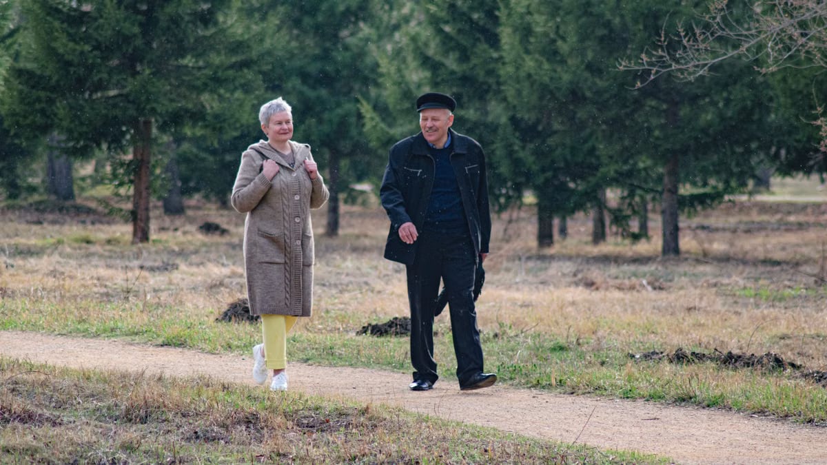 Happy senior couple strolling along a park path on a pleasant spring day.